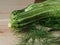 Overhead shot of a group of  isolated three green biologic zucchini veggies fruit over a light brown table and a paper recycled