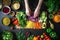 Overhead shot of hands chopping red onion amidst variety of vegan ingredients on black background