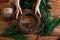 Overhead shot of hands making handmade Christmas wreath with twigs, pine cones, cinnamon sticks