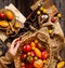 Overhead shot of homegrown assorted red, yellow, orange tomatoes in wicker straw basket in woman hands