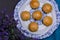 Overhead shot of mini pies in a china plate next to a white vase full of lavender