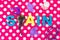 Overhead shot plastic letters and castanet spelling [SPAIN} purple ornaments pink dotted background