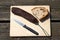 Overhead shot of a slice of bread, dried sausage, and a knife on a cutting board