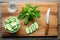 overhead shot, sliced cucumbers, mint sprigs on a wooden board, a glass filled beside