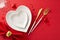 Overhead shot of sophisticated table arrangement for Valentine\\\'s Day heart-shaped plates, napkin on red backdrop