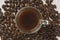 Overhead shot of a transparent espresso cup with drink on a group of coffee beans