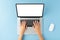 Overhead shot of womanâ€™s hands using laptop with blank display on blue background. Modern workspace concept.