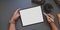 Overhead shot of young man working on blank screen tablet in dark trendy workspace