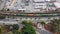 Overhead tilt shot of cars and trucks driving along a street surrounded by a train on railroad tracks and lush green trees