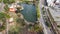 overhead tilt shot of a silky green lake at Lincoln Park with cars and trucks driving along the street and office buildings