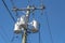 Overhead transformer bank with three white distribution transformers on pole with blue sky