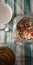 Overhead vertical shot of colorful cereal in a jar, a spoon and a white bowl on a tablecloth