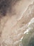 Overhead vertical shot of a man walking away from the water on a beautiful beach