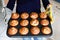 Overhead view of a baking tray with freshly prepared plain chocolate vanilla muffins holding by a child