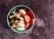Overhead view of a bowl with plain Greek yogurt candy trail mix bananas and strawberries on a marron tabletop illuminated with