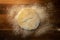 Overhead view of bread dough ball on a wooden cutting board with flour.