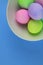 Overhead view of brightly painted easter eggs in a white bowl on blue background
