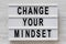 Overhead view, `Change your mindset` words on a lightbox on a white wooden background. From above, flat lay, top view