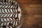 Overhead view close up food photography of a homemade Bakewell tart with iced chocolate top and red cherries on wood background