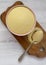 Overhead view, dry semolina durum flour in a pink bowl over white wooden surface. Top view, from above, flat lay. Closeup