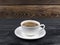 Overhead view of a freshly brewed mug of espresso coffee on rustic wooden background with woodgrain texture. Coffee break style