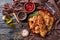 Overhead view of hash brown crusted pork chops on a clay plate on a rustic wooden table with tomato sauce in a bowl, view from