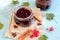 An overhead view of an open jar of homemade redcurrant jam or preserves, next to cinnamon sticks and anise stars. Hard light. Blue