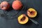 Overhead view of peaches in black wire basket, halved peach, knife