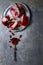 Overhead view of a pomegranate opened on a pewter plate with juicy red seeds scattered around and on a tarnished silver spoon.