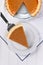 Overhead view of a slice of Pumpkin pie on a serving spatula the rest of the pie is at the top of the frame. Vertical fomat on a