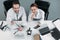 overhead view of smiling scientific researchers in white coats looking at camera at workplace