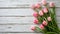 Overhead view of a springtime pink tulips on white weathered wooden boards, top view