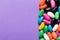 Overhead view of sweet multi colored candies by copy space on purple background