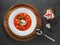 Overhead view to Red ukrainian borscht in white plate on wooden plate with dark bread and garlic