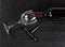 Overhead view of vintage corkscrew with red wine bottle and drinking glass on black slate background