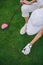 overhead view of woman in cap and golf glove putting ball on green lawn