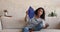 Overheated Latin woman falling on sofa cooling herself with fan