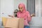 Overjoyed black muslim woman unpacking delivery box, satisfied customer opening package at home