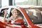 Overjoyed driver woman smiling and showing new car key while sitting in a car