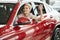 Overjoyed driver woman smiling and showing new key while sitting in car showroom