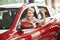 Overjoyed driver woman smiling and showing new key while sitting in car showroom