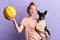 Overjoyed excited ginger girl teaching her dog to play with a ball