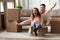 Overjoyed family couple having fun together in new living room.