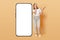 Overjoyed funny laughing woman with brown hair standing near big smartphone with empty display holding mobile phone in hands copy