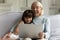 Overjoyed grandmother and cute granddaughter watch funny video on laptop