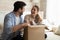 Overjoyed laughing millennial husband and wife unboxing packages after relocation