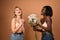 Overjoyed lovely young european lady receives congratulation and flowers on birthday, african smiling woman stretches