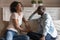 Overjoyed millennial african american married couple sitting on sofa, chatting.