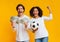 Overjoyed multiracial couple celebrating success with money cash and soccer ball
