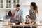 Overjoyed parents with little kids have fun cooking in kitchen